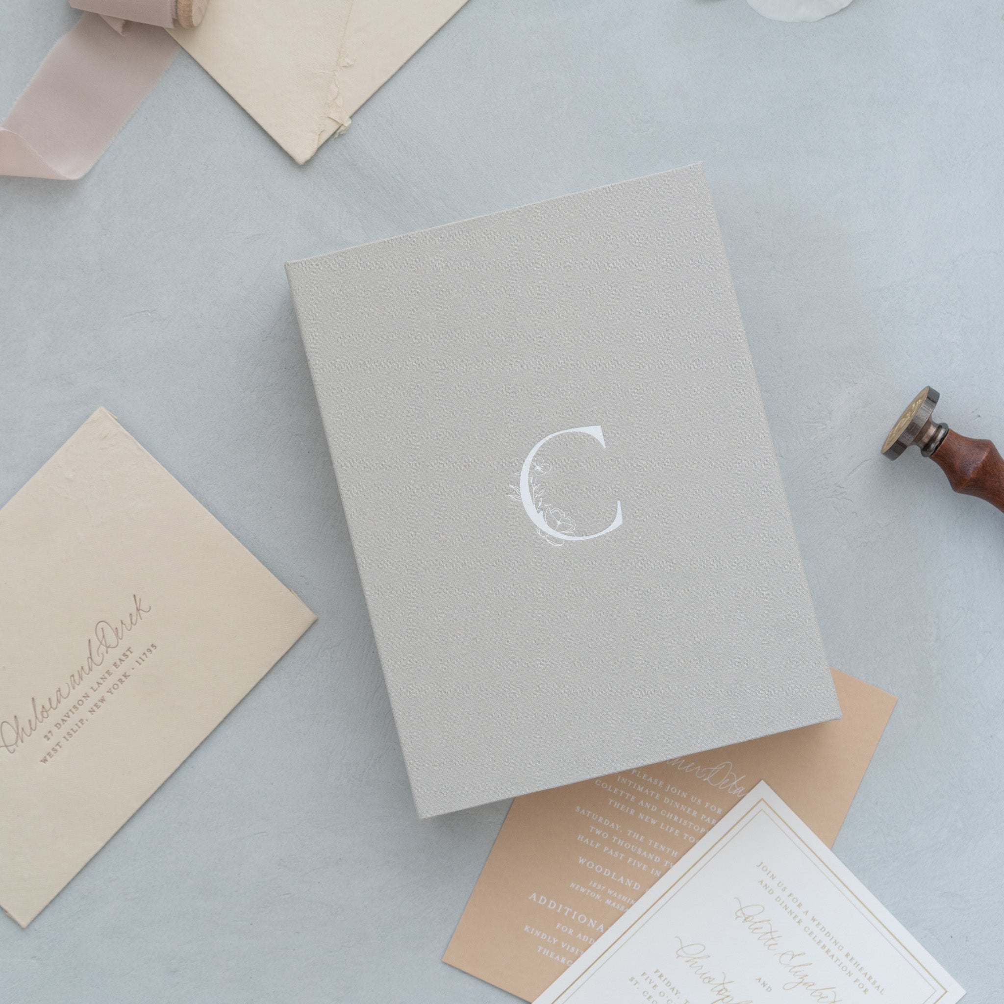 various stationery items, including a gray envelope with a white letter "C" on it, a brown envelope, and a white card with text.