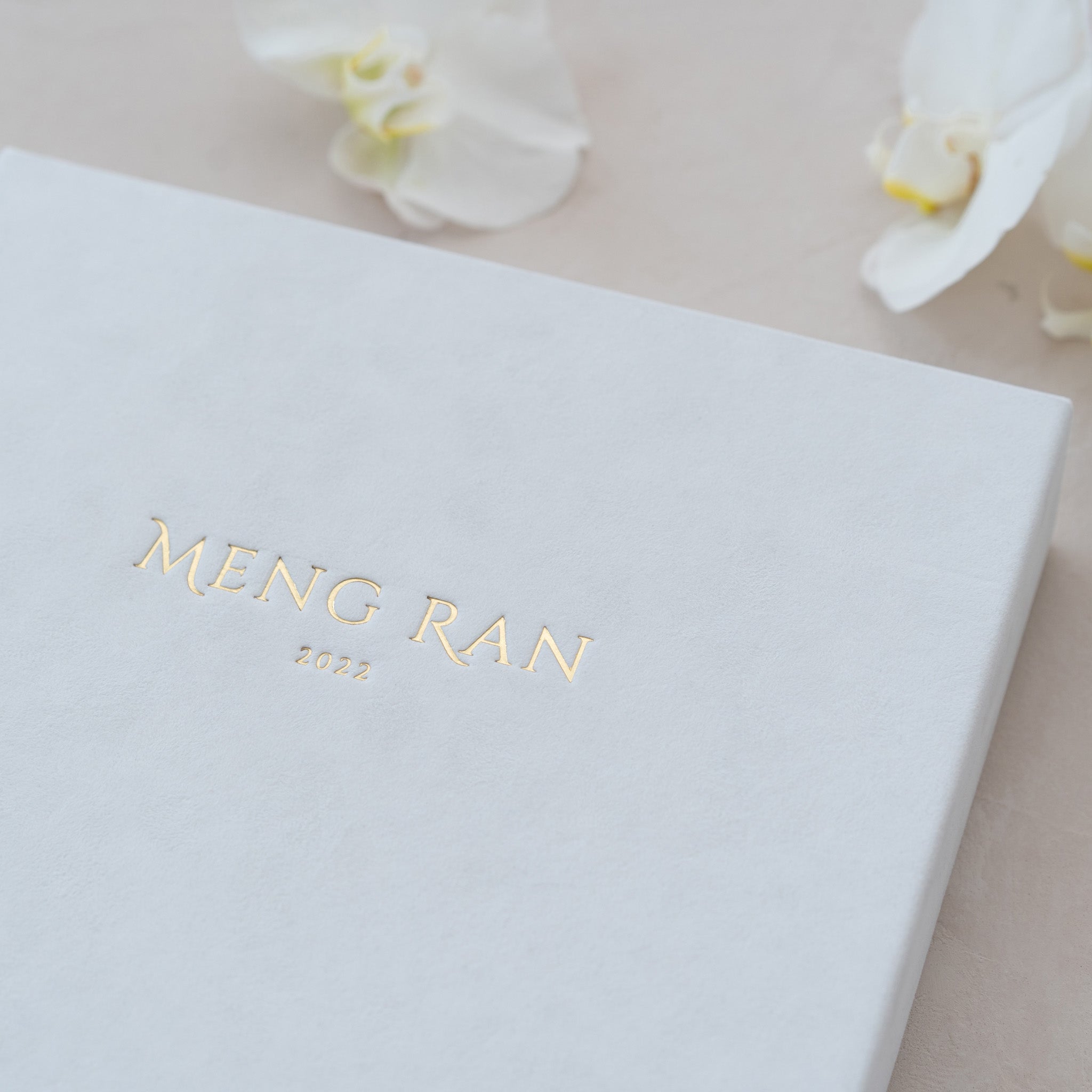 A white box with gold text and a small white flower on the side.