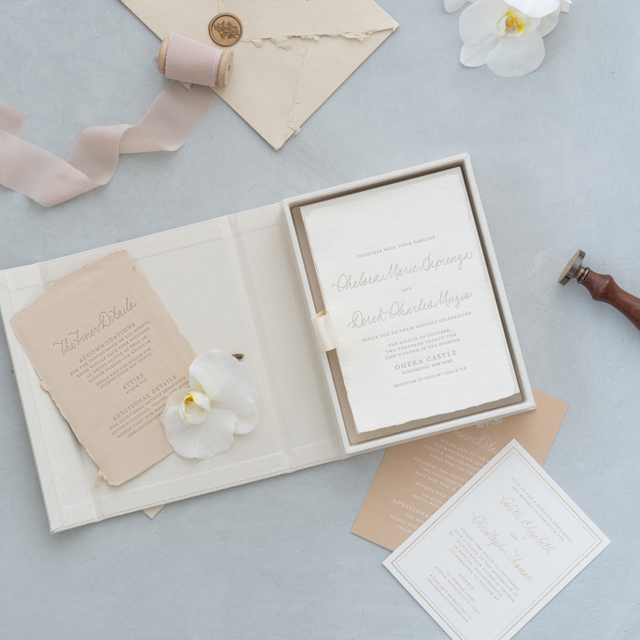 a wedding invitation with a white background and gold lettering, along with some additional wedding-related items such as a ribbon, a flower, and a stamp.