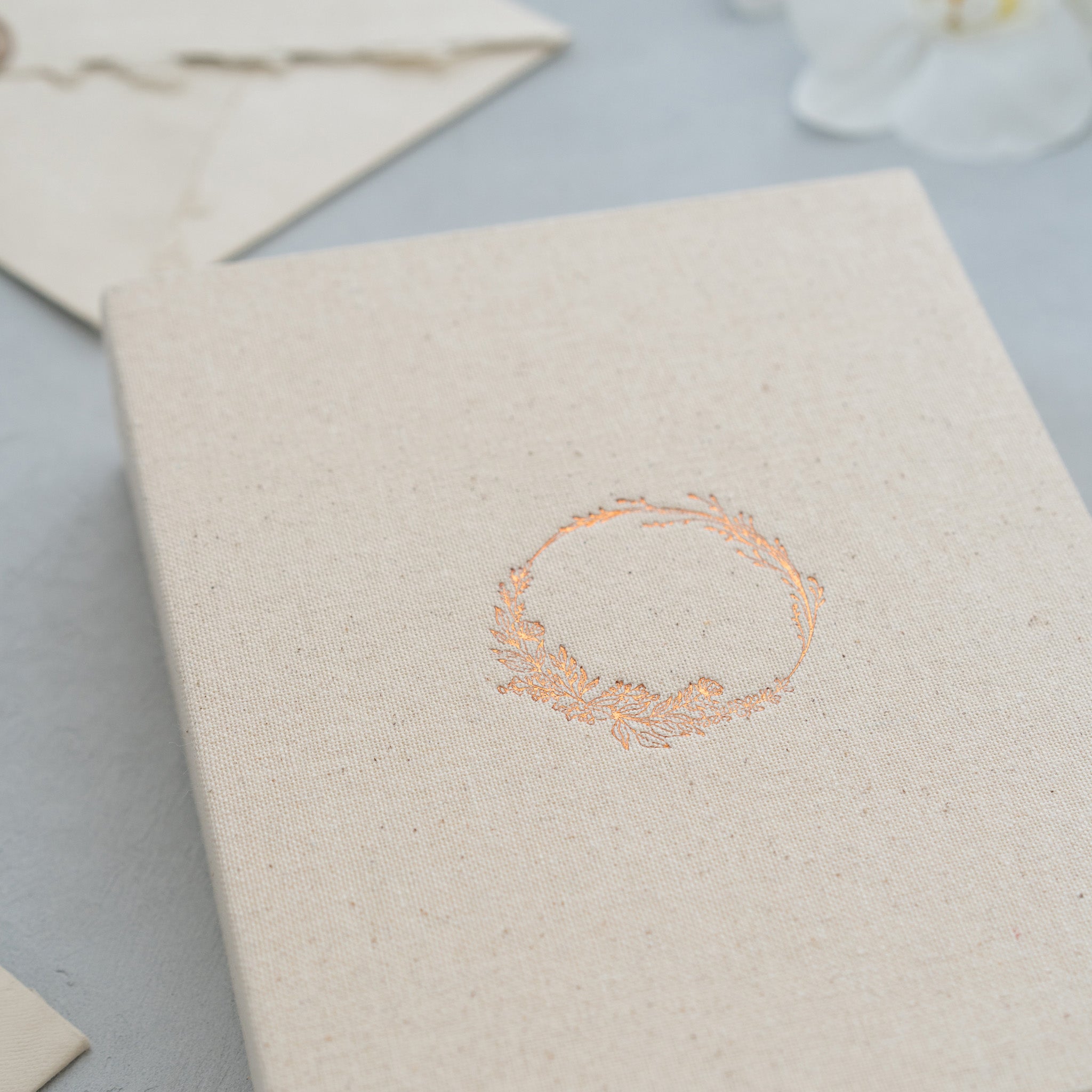 A close-up image of a cream-colored book or card with a decorative floral design on the cover.