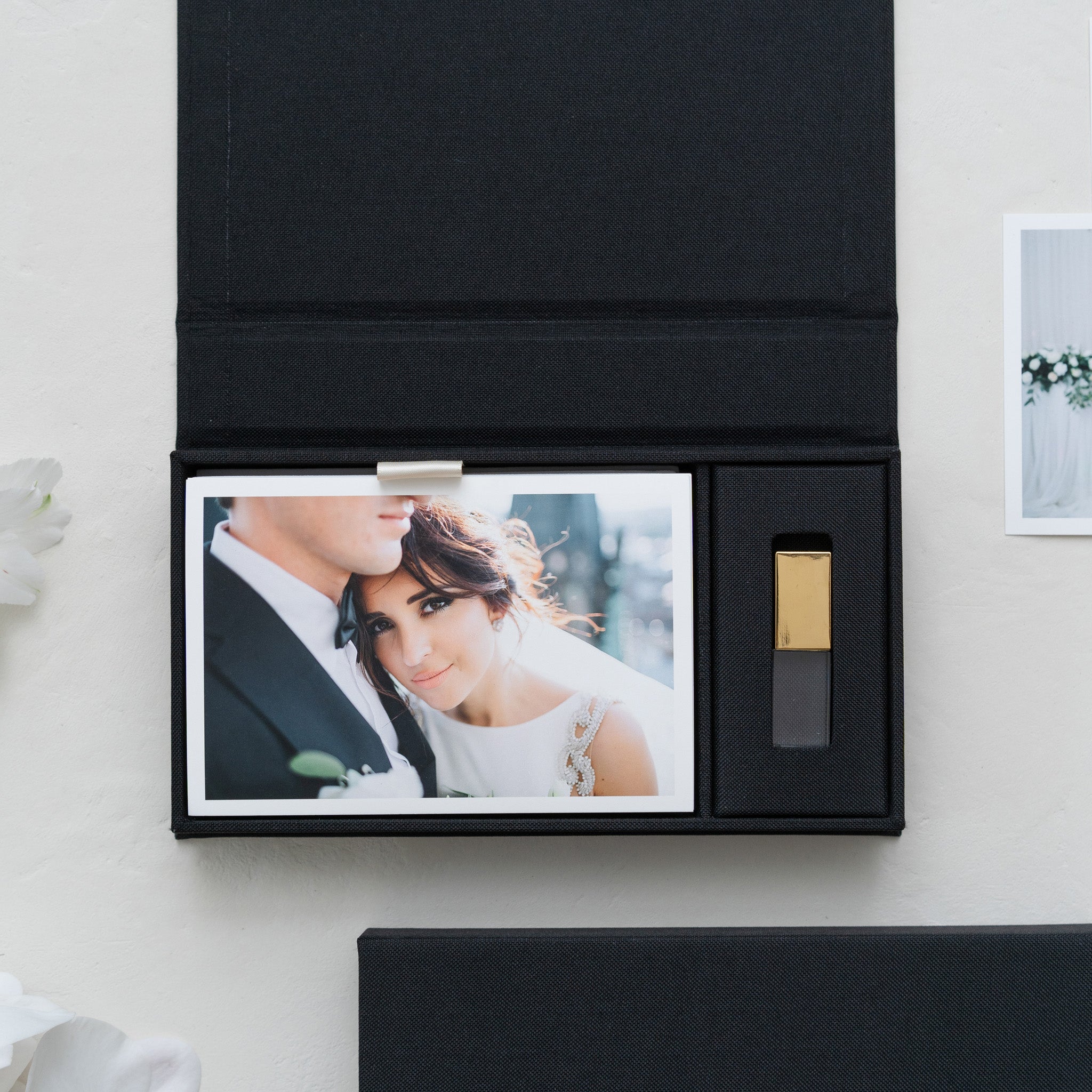 A black photo album with a printed photograph of a couple inside, placed on a white surface.