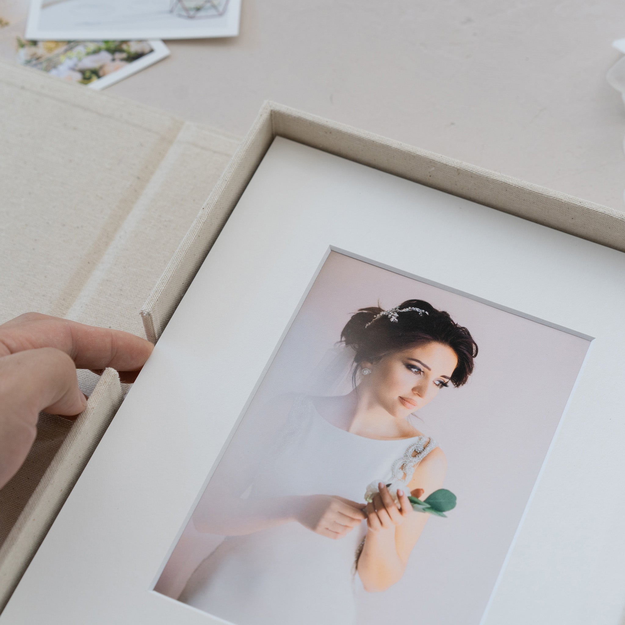 A hand is holding a white photo frame with a picture of a woman inside it.
