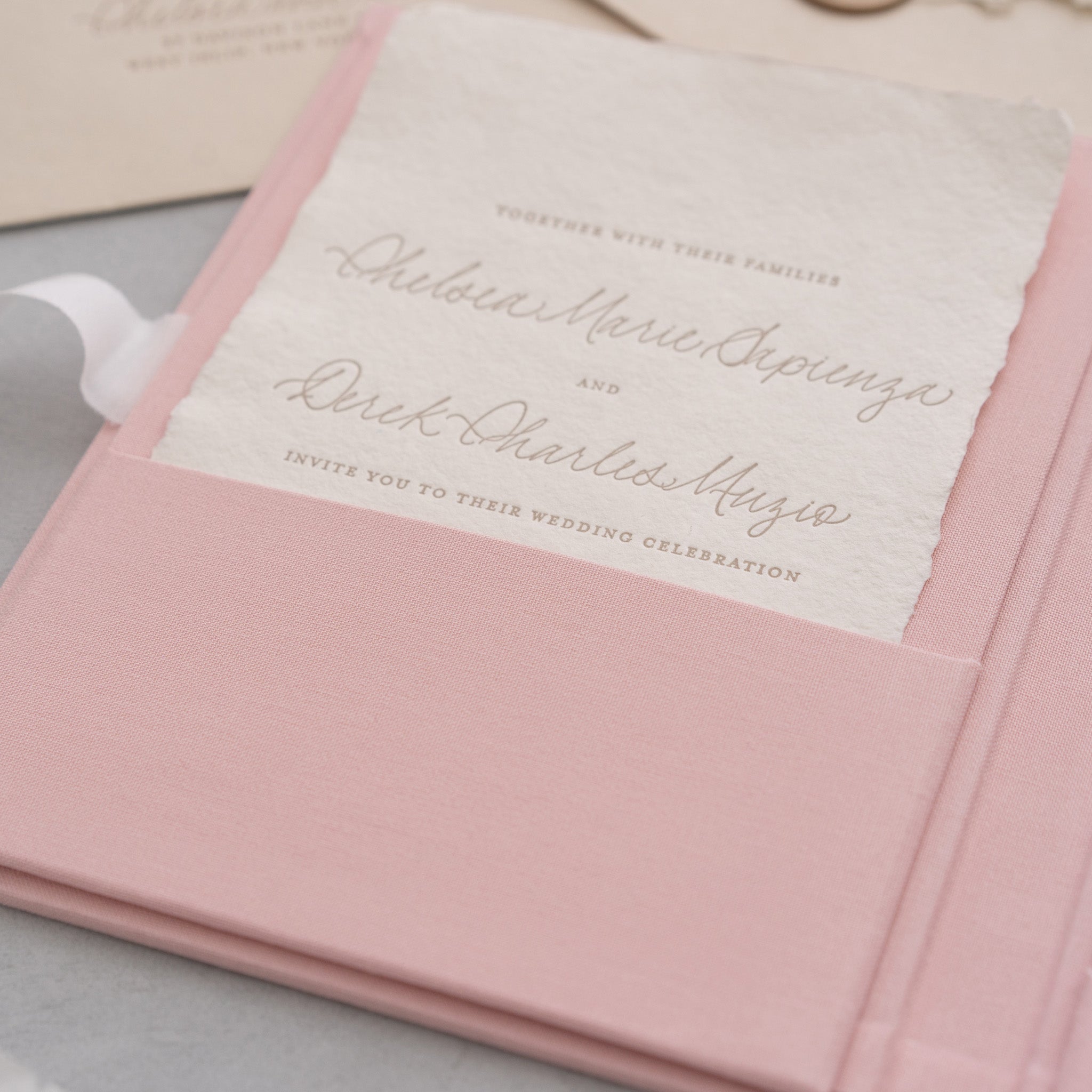 A pink wedding invitation card with cursive text inviting guests to a wedding celebration.