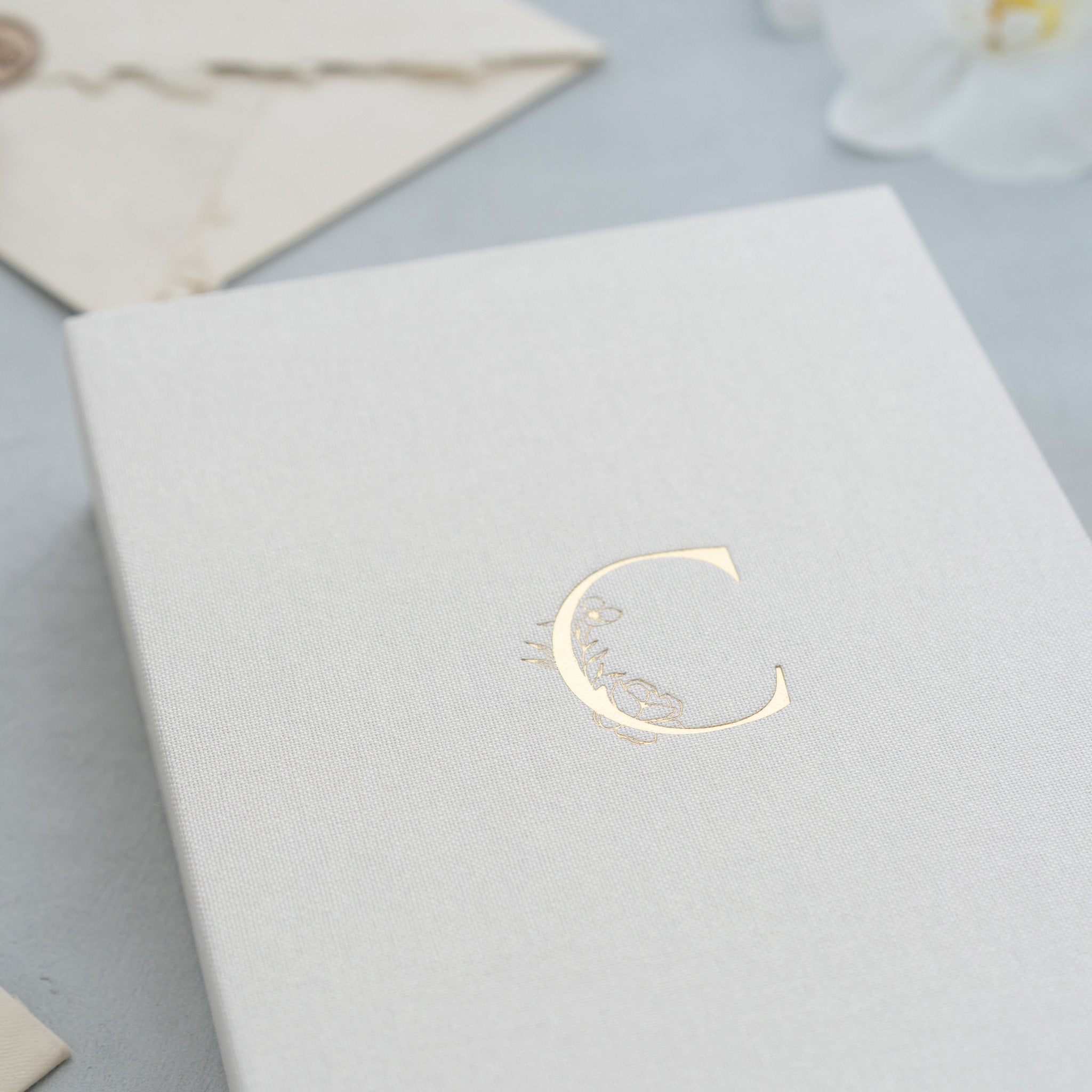 A close-up image of a white book or notebook with a gold letter 'C' embossed on the cover.